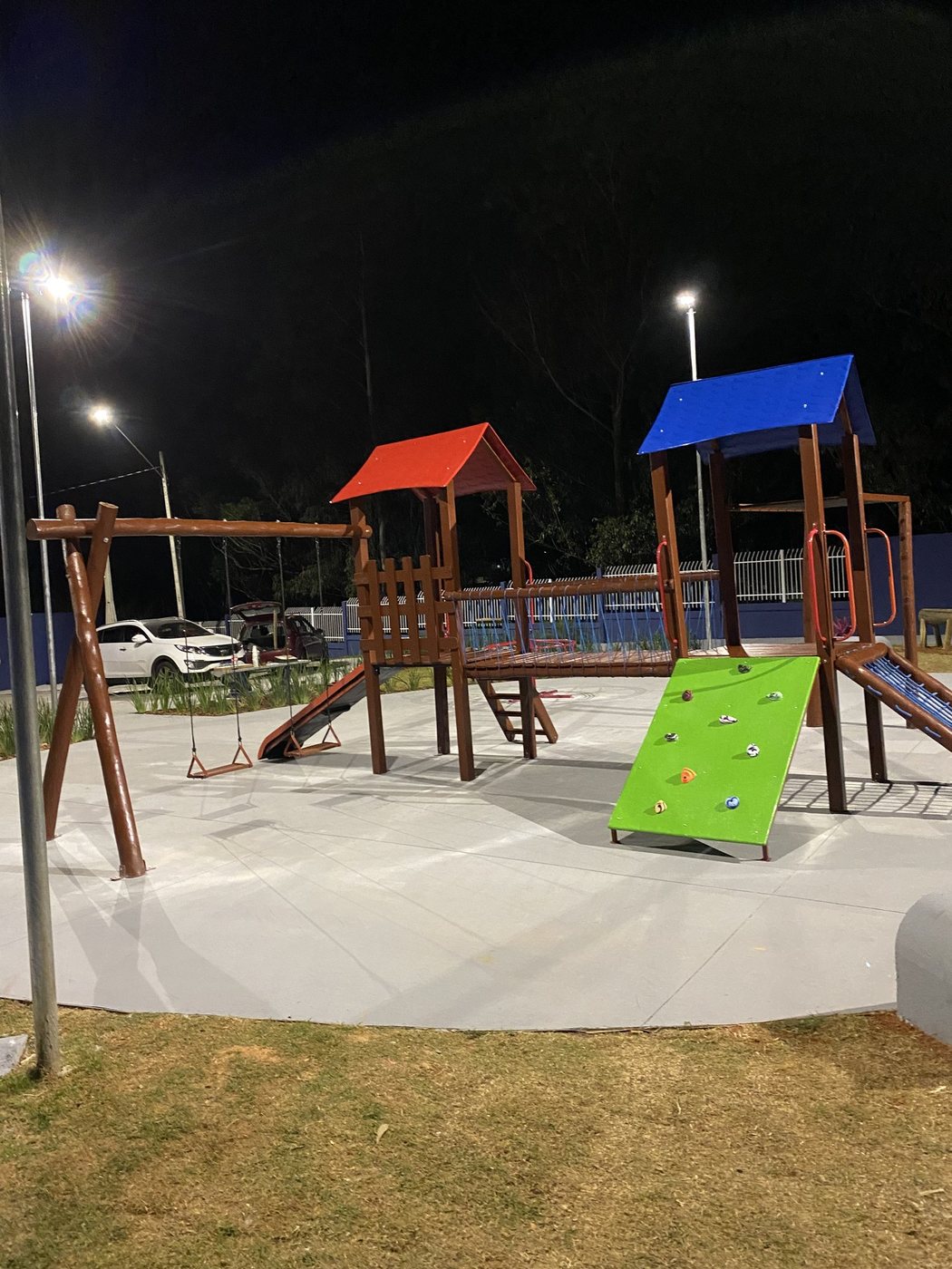 Playground de madeira de eucalipto à noite, com balanço suspenso em travessa de madeira